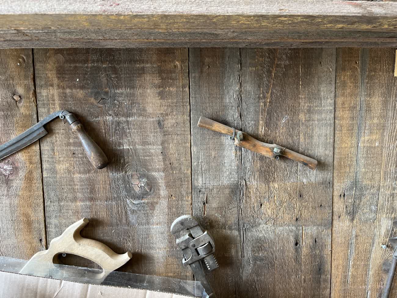 Old hand tools hung on a weathered wooden wall