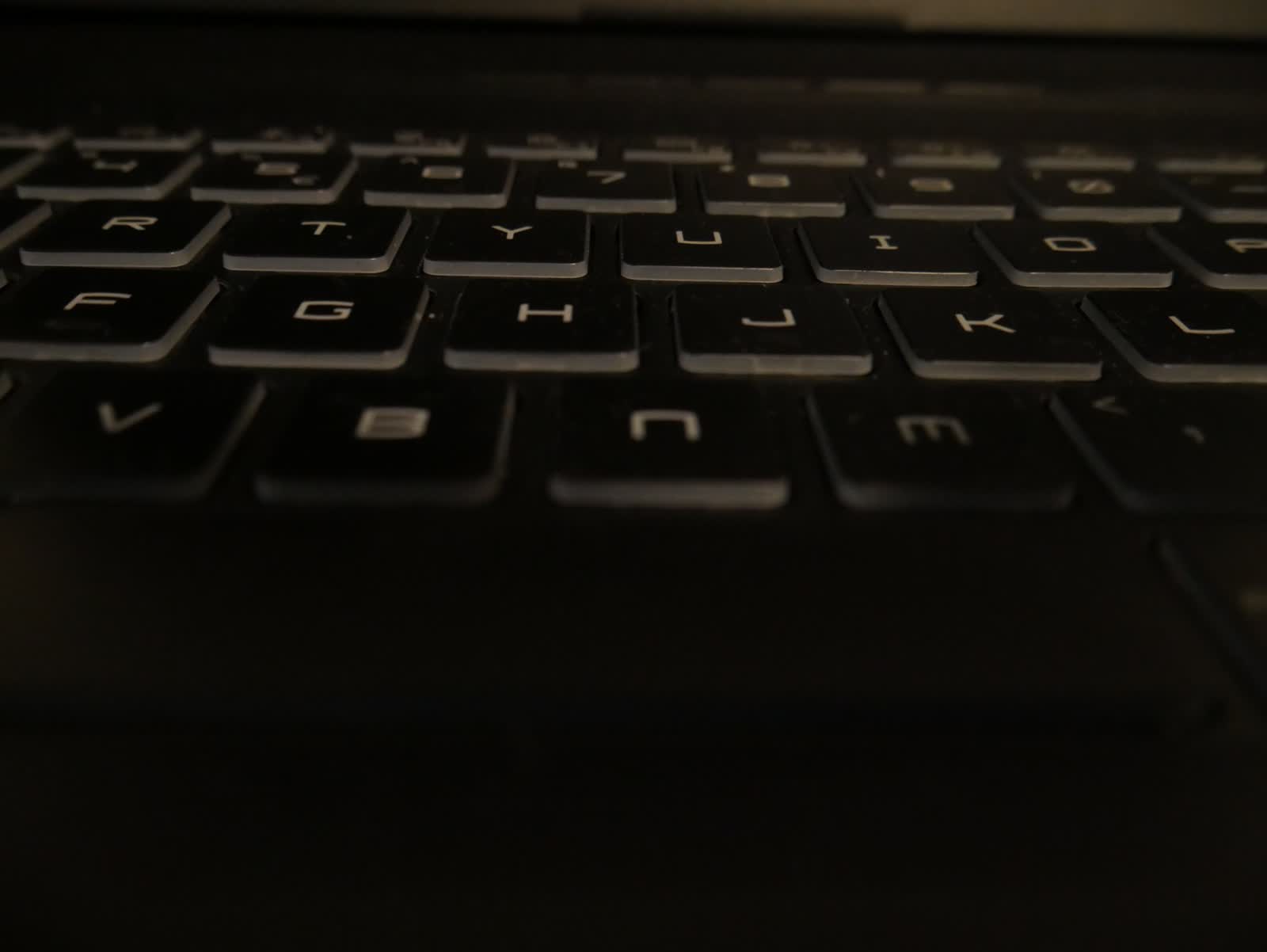 Close-up of a dimly lit black laptop keyboard