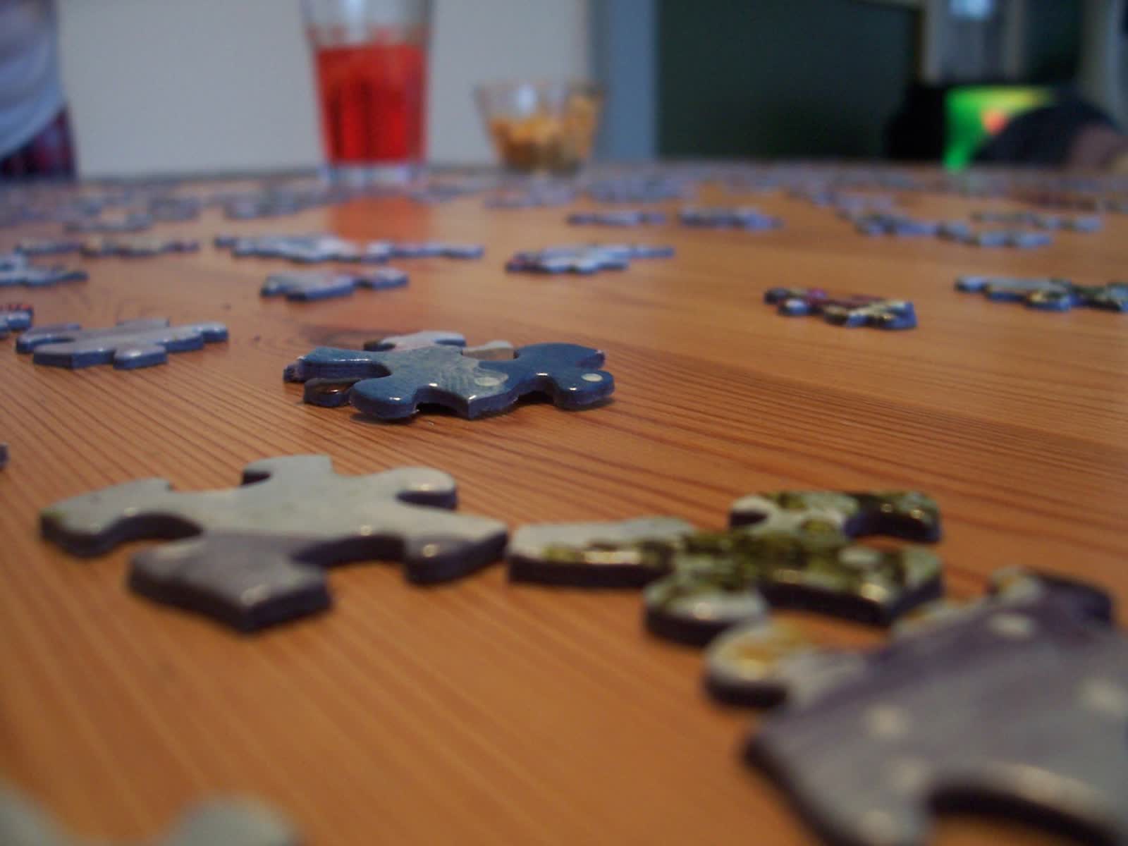 Jigsaw puzzle pieces scattered across a wooden table