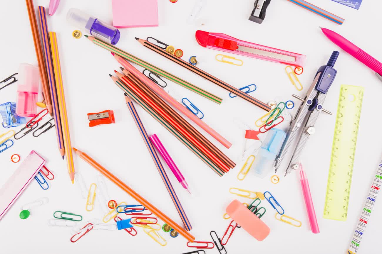 Colorful pencils, paper clips, a ruler and sticky notes scattered on a white surface