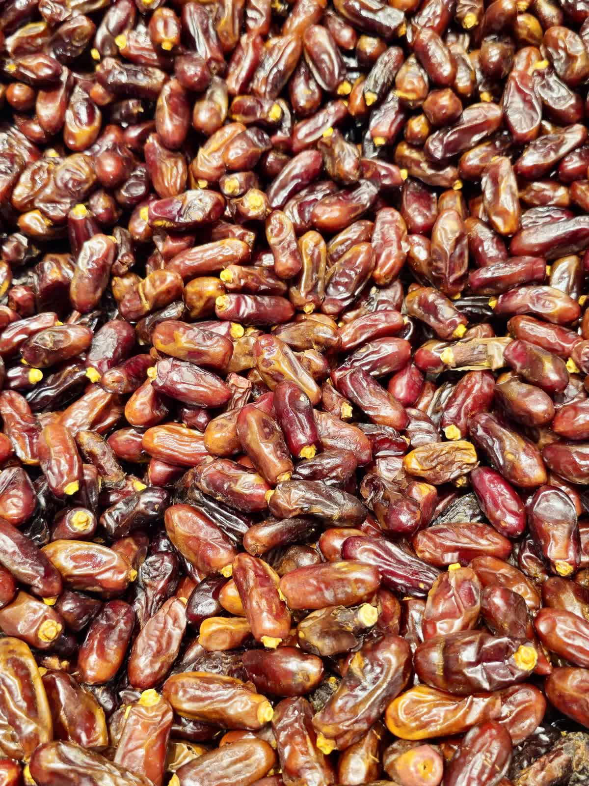 A close-up pile of dark reddish-brown dried dates