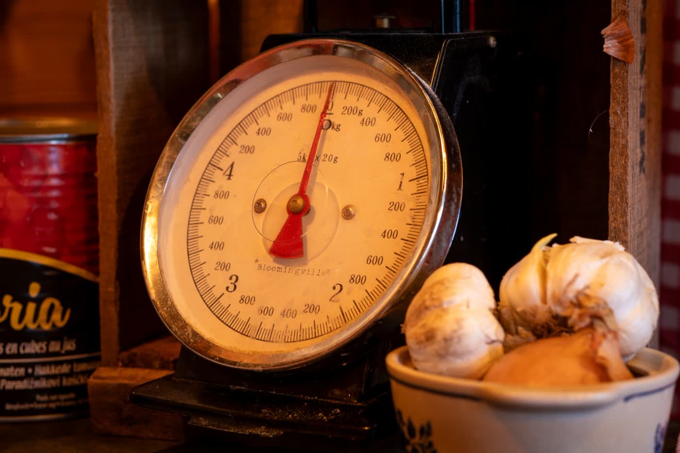 A vintage dial kitchen scale next to a bowl of garlic bulbs